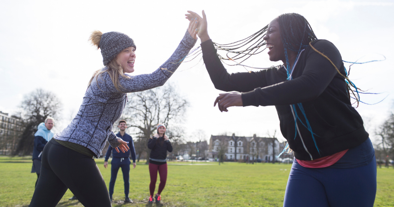Two women high five in a field