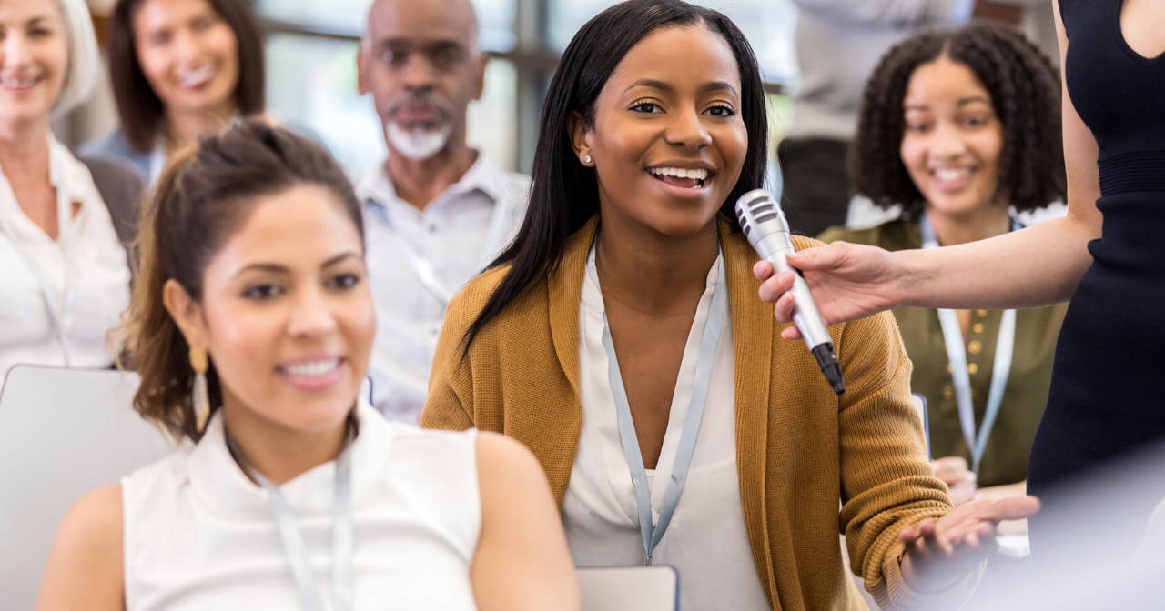 A woman asks a question at a town hall event. 