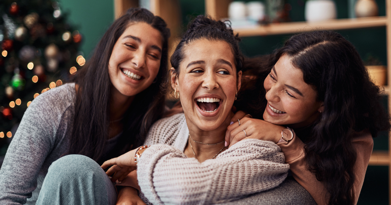 Three sisters laugh in their living room. 
