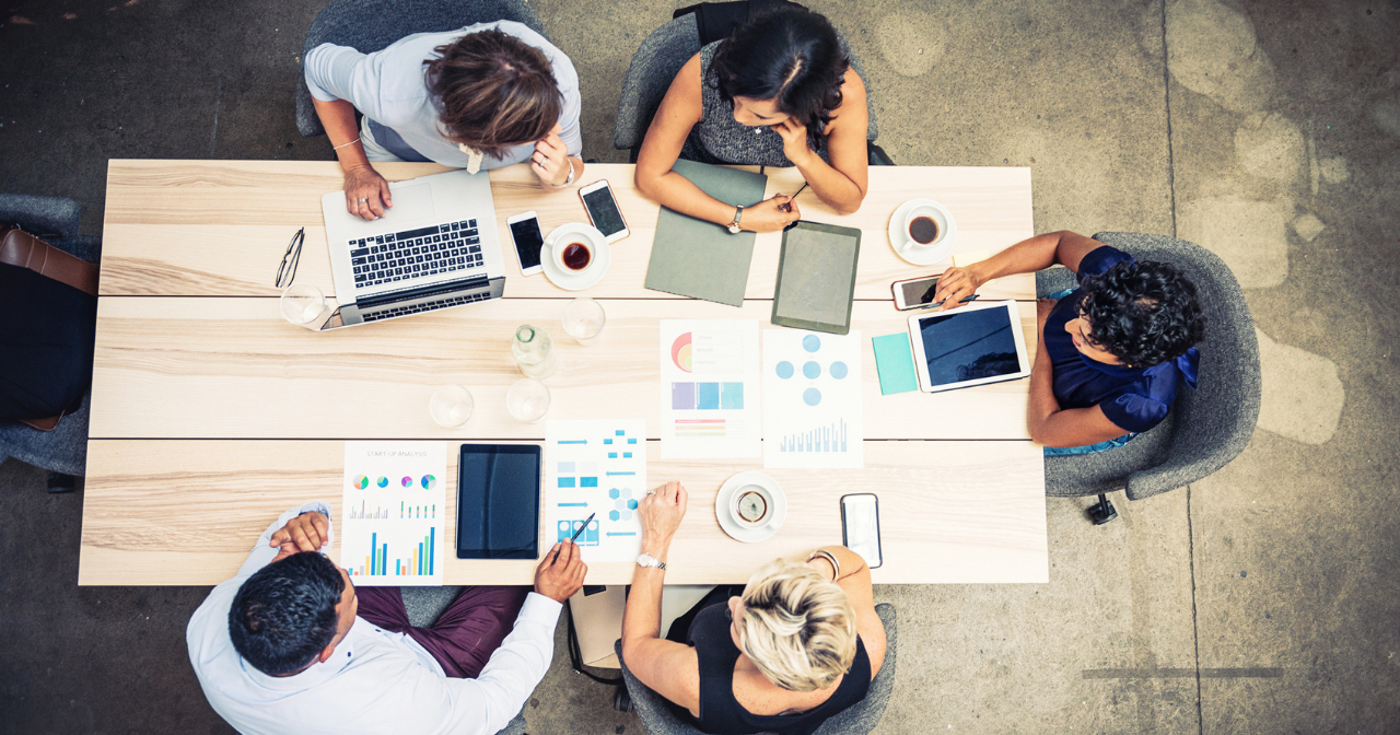 A group of five people works together at a table. 