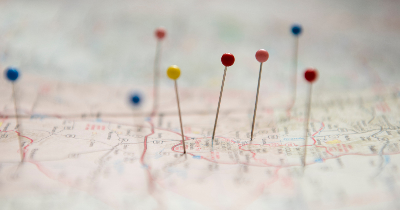 A paper map with pins of different colors stuck in different places. 