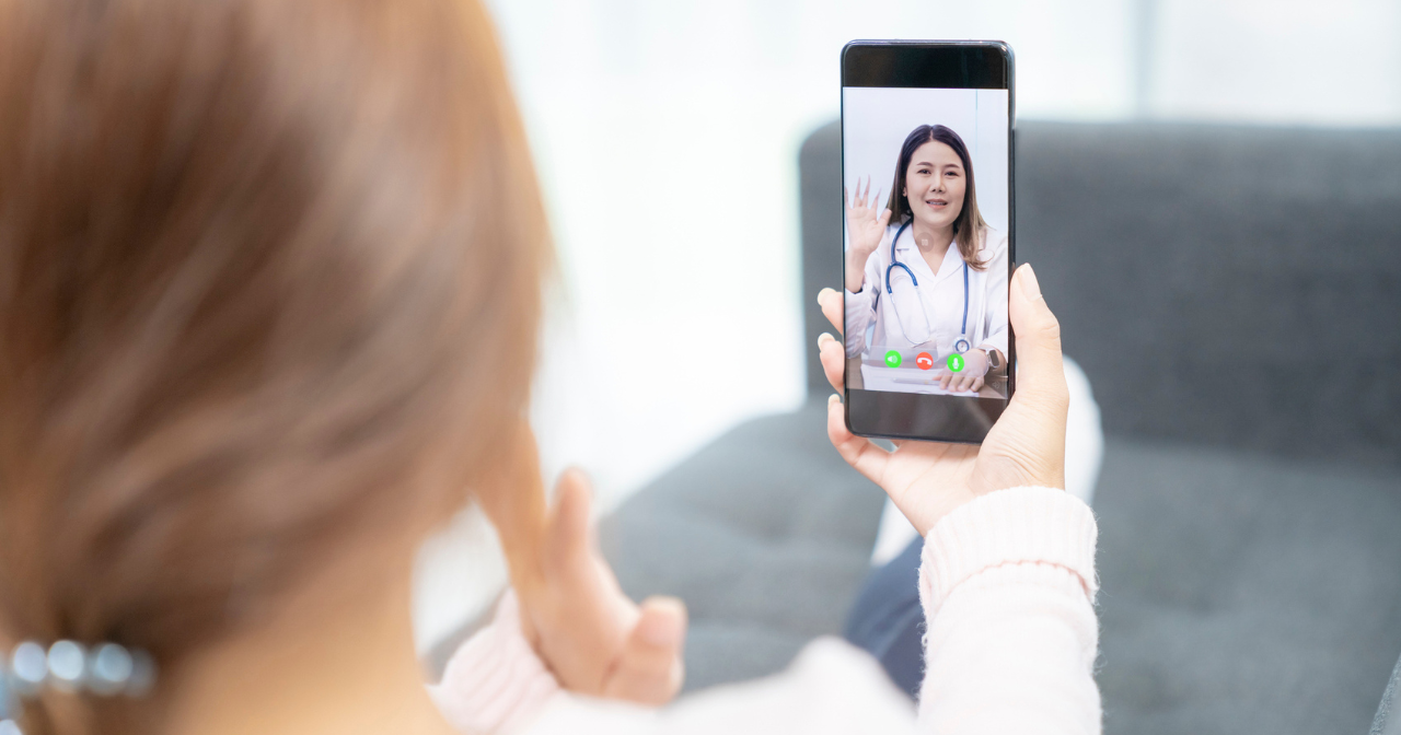 A photo of the back of a woman's head looking over her shoulder to see a health care provider on the phone in her hand. 