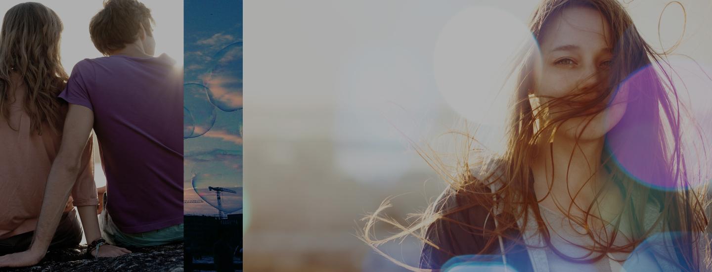 A couple sits with their back to the camera and a girl smiles at the camera with a lens flare