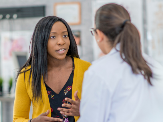 A woman and her provider talk in an exam room