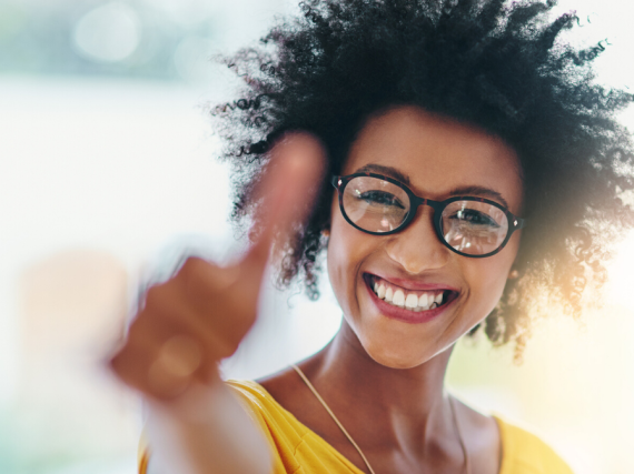 A black woman smiles and gives a thumbs up