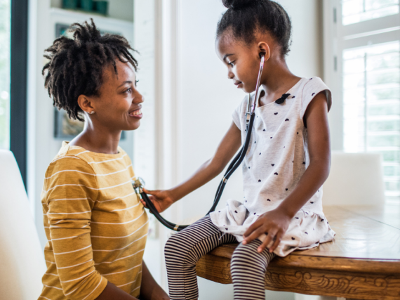 A Black woman and her daughter explore with a stethoscope. 