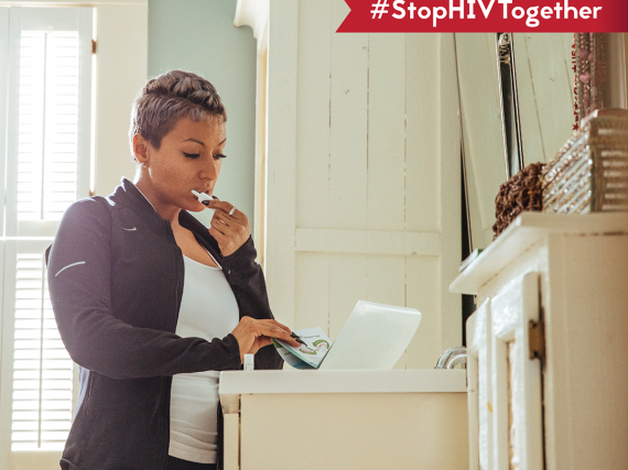 A woman stands in her bathroom and reads the instructions on an at-home HIV testing kit. 