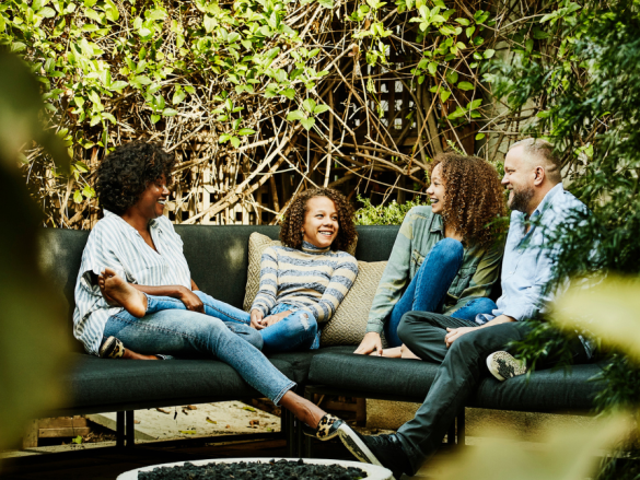 A family of four sits outside and talks and laughs together. 