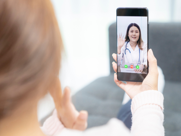 A photo of the back of a woman's head looking over her shoulder to see a health care provider on the phone in her hand. 